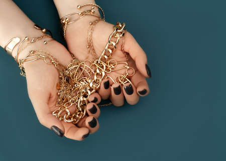 Female hands with trendy dark nail design with gold bracelets on aqua background. Luxury concept. Festive backdrop for your design. Top view.の写真素材