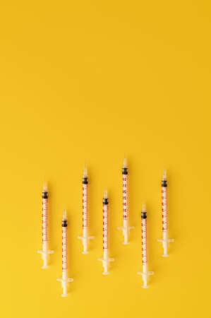 Syringes on trendy yellow background. Cosmetology and medicine background. vaccine concept. Top view.の写真素材