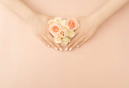 Female hands holding tea roses on pastel background for decoration design. Vintage pink gift card. Love and romance concept. Beauty concept. Flat lay style. Copy space.の写真素材