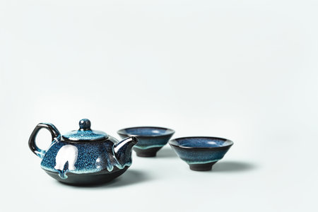 Green tea in a dark blue clay teapot and two small cups on pastel background. Creative minimalist tea ceremony concept. Copy space.の写真素材