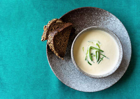Clay bowl of Finnish salmon cream soup served with leek and croutons on green tablecloth background. Healthy food concept. Food background with copy space. Close up, selective focus.の写真素材