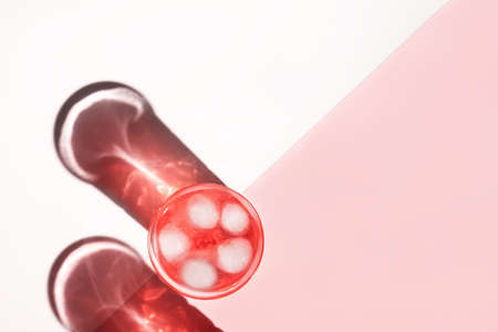 Two beautiful crystal glasses cast long shadows from sunlight on white and pink background. Minimal creative composition in flat lay style with copy space. Summer drinks concept.の写真素材