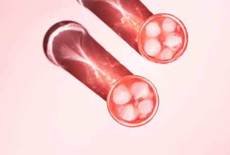 Two beautiful crystal glasses cast long shadows from sunlight on pink background. Minimal creative composition in flat lay style with copy space. Summer drinks concept.の写真素材