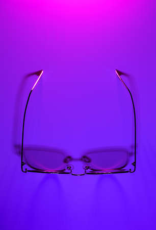 Stylish gold and pink eye glasses with shadow on purple and pink gradient background. Flat lay style, top view. Copy space for your text. Minimal summer concept.の写真素材