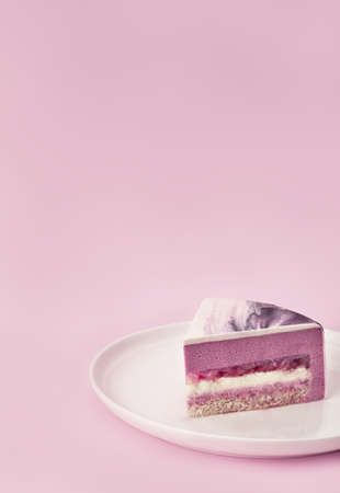 Delicious litchi and raspberry mousse cake slice with the layers and texture displayed on lilac...