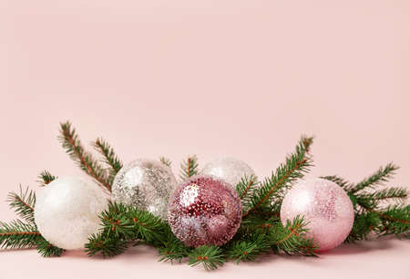 Christmas decoration of fir tree branches with white and pink glass baubles on pastel pink background. Copy space.の写真素材