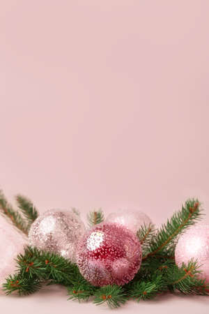 Christmas decoration of fir tree branches with white and pink glass baubles on pastel pink background. Copy space.の写真素材