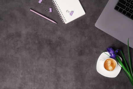 Spring women's workspace top view with beautiful iris flowers, laptop, notepad, pen and coffee on...