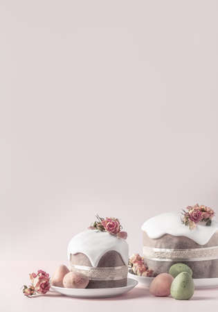 Glazed Easter cakes decorated with dry tea rose flowers on pastel pink background. Easter composition with cakes, roses and chocolate eggs. Easter background with copy space for your design.の写真素材