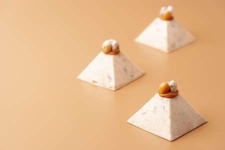 Traditional cottage cheese dessert Paskha decorated with caramel and chocolate candy eggs on pastel background. Modern minimalistic Easter background with copy space for your design.の写真素材