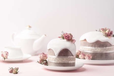 Glazed Easter cakes decorated with dry tea rose flowers on pastel pink background. Easter...
