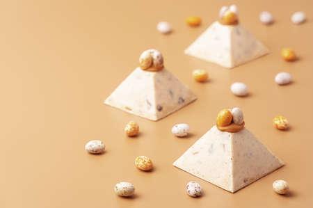 Traditional cottage cheese dessert Paskha decorated with caramel and chocolate candy eggs on pastel background. Modern minimalistic Easter background with copy space for your design.の写真素材