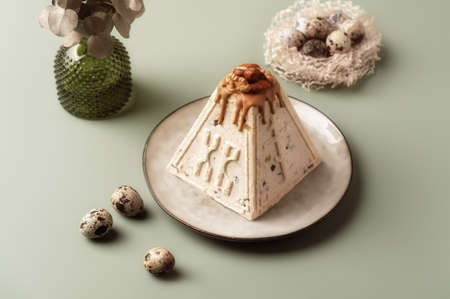 Traditional Easter cottage cheese dessert Paskha decorated with caramel, nuts, raisins and quail...