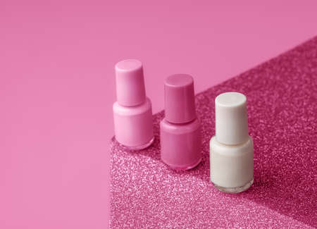 Trendy design template with nail polish glass bottles on pink and sparkling background. Manicure...