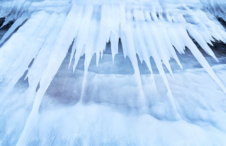 Blue ice and icicles on the rocks of Ogoy island, Baikal lake, Siberia, Russia. Abstract winter...