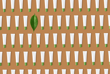 Creative seamless pattern of white cosmetic tubes and green leaf on sand colored background....