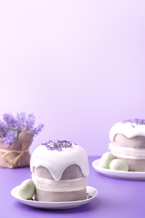 Glazed Easter cakes decorated with lavander flowers and chocolate eggs on bright violet background. Holiday background with copy space for your design.の写真素材