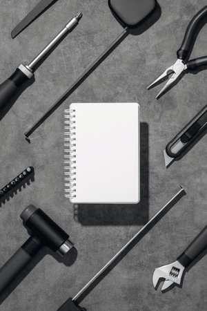 Flat lay composition with set of home repair tools and opened notebook on grey stone background. Top view pattern with copy space.の写真素材
