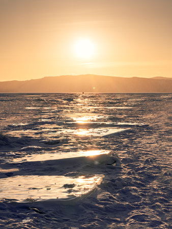 Winter landscape with ice hummocks glittering in the sun and mountains of Lake Baikal in Siberia at sunset. Natural background with copy space.の写真素材