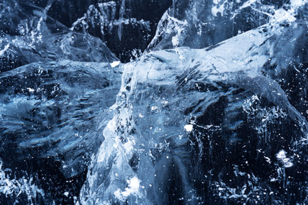 Transparent dark blue ice of frozen Baikal lake with white cracks pattern. Beautiful winter nature...