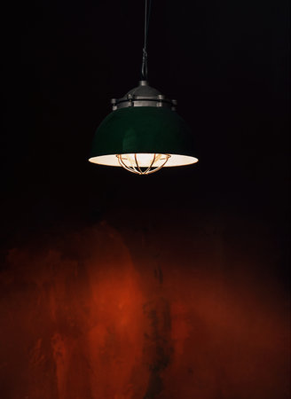 Minimal retro style green metallic pendant lamp on red wall background. Vintage building interior concept with copy space.の写真素材