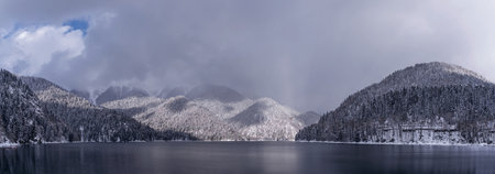 Beautiful winter panorama with mountain Ritsa lake and snow-covered trees along the shore. Great natural background with copy space for your design.の写真素材