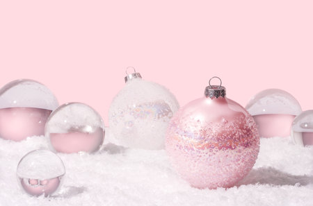 Transparent glass orbs and Christmas balls with snow on pink background. Christmas decor concept.の写真素材