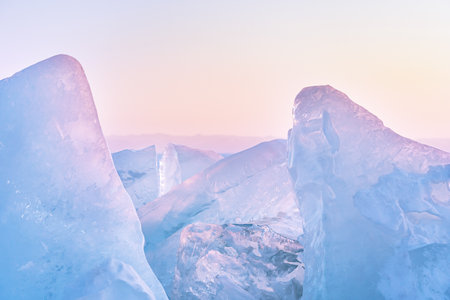 Winter landscape with ice hummocks glittering in the sun and mountains of Lake Baikal in Siberia at sunset. Natural background with copy space.の写真素材