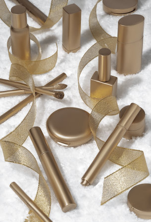 Luxury composition of golden cosmetic products and party streamers on white snow background. Holiday background. Beauty concept.の写真素材