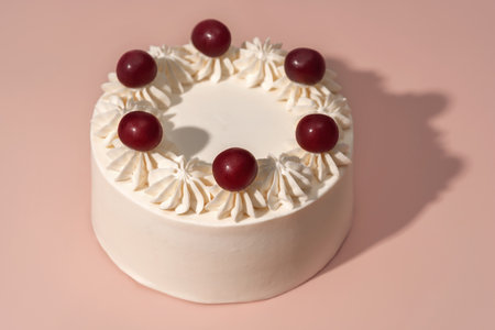 Bento cake adorned with cherries and chocolate accents, surrounded by fluffy whipped cream rosettes,...