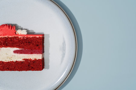 Red velvet cake slice presented on a round white plate, highlighting layers of sponge and creamy...