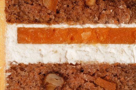 Bento cake showcases layers of rich carrot cake interspersed with creamy filling and bright orange and mango elements, emphasizing texture and color in a delightful culinary presentationの写真素材