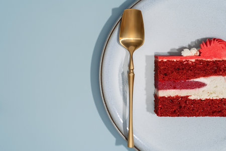 Slice of red velvet bento cake displayed on a textured plate with a golden spoon, highlighting...