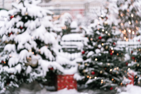 Blurred Christmas background featuring softly focused snow-covered trees adorned with lights, creating a serene atmosphere perfect for holiday-themed designs and seasonal greetings with copy spaceの写真素材