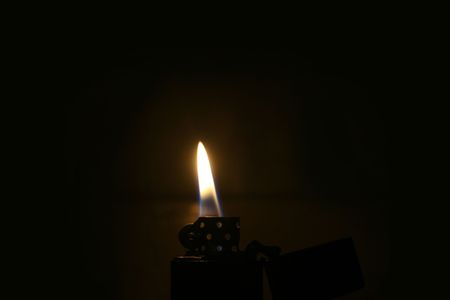 Zippo lighter with flame in dark roomの写真素材
