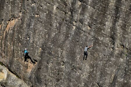 Climbers on an almost vertical wall of a mountainの写真素材