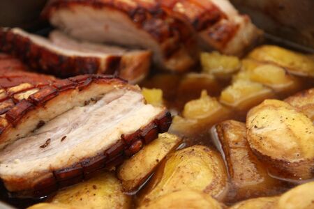 Homemade roast pork belly with fried potatoes sliced ââin juice close upの写真素材