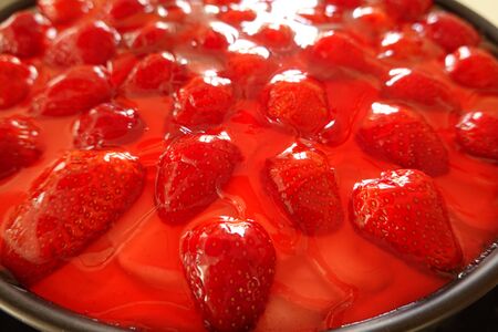 Strawberry cake in a black spring form pan - close up of jelly fruit topping, a detail view of a tasty fresh homemade cac with many red strawberriesの写真素材