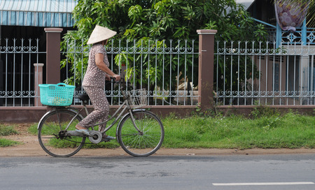 CAN THO, VIETNAM - MAY 28, 2014. Unidentified woman rides bicycle along Mekong in Can Tho, Vietnam. In 1999, Transportation Police Bureau estimated some 20 million bicycles in Vietnam.のeditorial素材