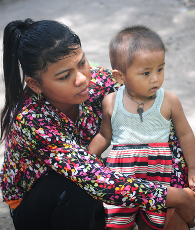 HA GIANG, VIETNAM - MAR 14, 2015. An unidentified Vietnamese minority child hugging his mother while eating rice at a weekly traditional flea market in Dong Van rocky plateau.のeditorial素材