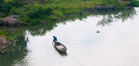 Mekong Delta Vietnam  Mar 13 2011. A man sitting on small boat harvesting vegetables on river in Mekong Delta southern Vietnam.のeditorial素材