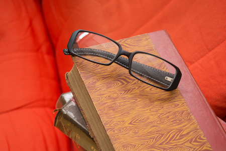 Stack of books with glasses on chair in living room.
