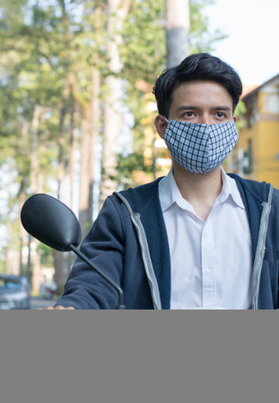 An Asian man wearing a mask to lessen the effect of toxic, traffic pollution in many Asia city..の写真素材