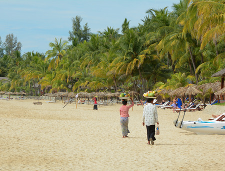 NGAPALI MYANMAR  JAN 16 2015. Unidentified woman selling fresh fruits at the shoreline to tourists in Ngapali beach. Selling products to the tourists is the main income for people in Ngapali.のeditorial素材