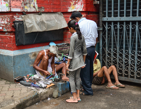 KOLKATA, INDIA - JUL 8, 2015. Unidentified shoe shiner does his job at street of Kolkata. Lots of people make their living by doing this job in India.のeditorial素材