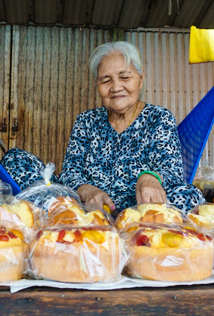 HAI DUONG, VIETNAM - APR 30, 2015. Elderly woman selling rice cakes in Gold market in Thanh Ha, Hai Duong, Vietnam. This is the oldest stock market in rural Vietnam was built in 1845.のeditorial素材