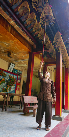 Saigon, Vietnam - May 22, 2015. An unidentified man offering incense sticks for the Gods in the Vietnamese Jade Emperor Pagoda in Ho Chi Minh city (Saigon), Vietnam.のeditorial素材
