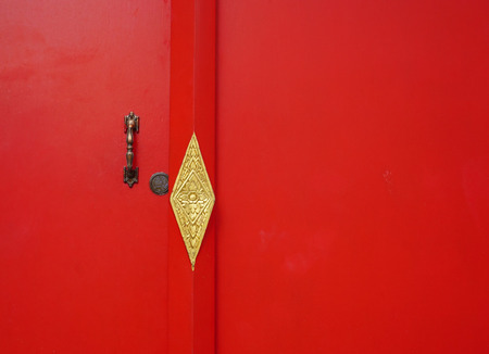 Red wooden door with texture and scratch at Khmer temple in Mekong Delta, southern Vietnam.の写真素材