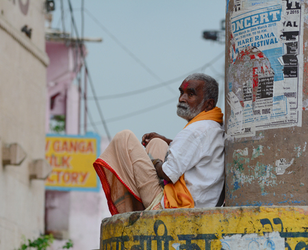 VARANASI, INDIA - AUG 12, 2015. An old man sitting and relaxing at the ghat nearby Ganges river in Varanasi, India.のeditorial素材