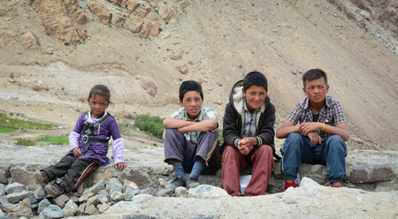 Leh, India - Jul 22, 2015. Group of Tibetan chidren sitting together on the road to Nubra Valley, India. 65% of children attend school, but absenteeism of both students and teachers remains high.のeditorial素材